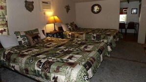 A room with two beds, a lamp, and a bear head decoration on the wall.