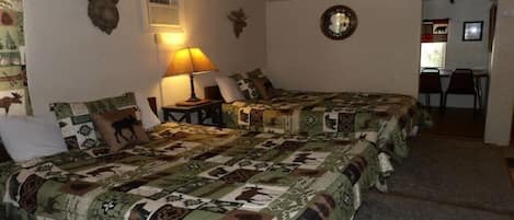 Una habitación con dos camas, una lámpara y una decoración de cabeza de oso en la pared.