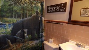 A bathroom with a bear mural, a sign that says "Please be sweet and wipe the seat," and a sink.
