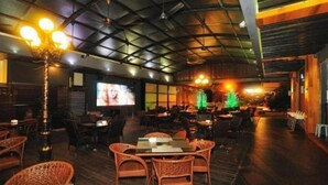 An indoor dining area with wicker furniture, a television screen, and decorative lights. - D North Star Hotel Spa (Sandakan)