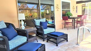 Eine Terrasse mit Korbmöbeln, einem Pool und einem Essbereich.