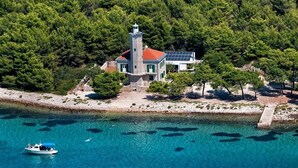 A coastal property with a lighthouse, a boat dock, and clear turquoise waters.