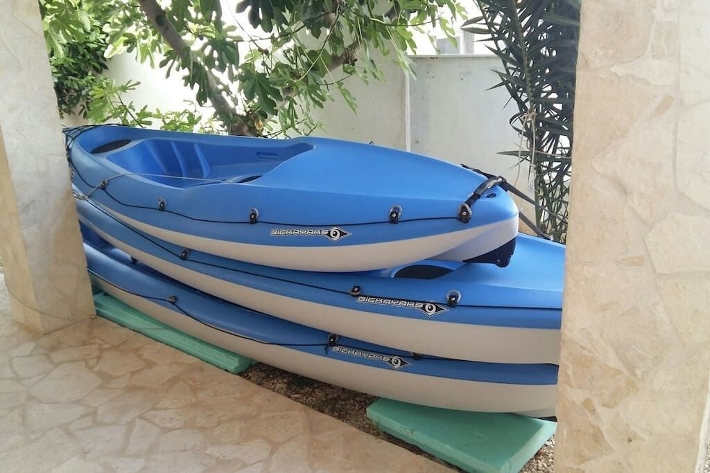 Une rangée de kayaks bleus et blancs est empilée sur une plateforme verte.