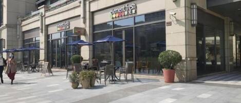 A storefront with outdoor seating and potted plants.