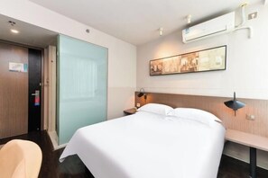 A hotel room with a bed, a desk, a chair, an air conditioning unit, and a wall-mounted picture. - Jinjiang Inn Select (Shanghai Zhangjiang High-tech Park) (Shanghai)