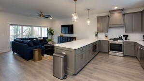A modern kitchen with a central island, stainless steel appliances, and a built-in oven. - Chic & Spacious Escape | East Nashville Stunner (Nashville)