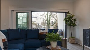 A modern living room with a blue sofa, a coffee table, and a potted plant. - Chic & Spacious Escape | East Nashville Stunner (Nashville)