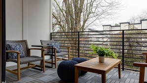 A balcony with wooden furniture, including chairs and a table, and a potted plant. - Chic & Spacious Escape | East Nashville Stunner (Nashville)