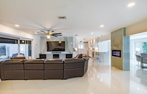 Relax in this stylish living room with a large L-shaped sofa, flat-screen TV, and sleek kitchen area.