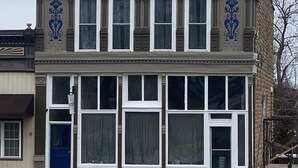 Un edificio de dos pisos con una puerta azul y ventanas grandes.