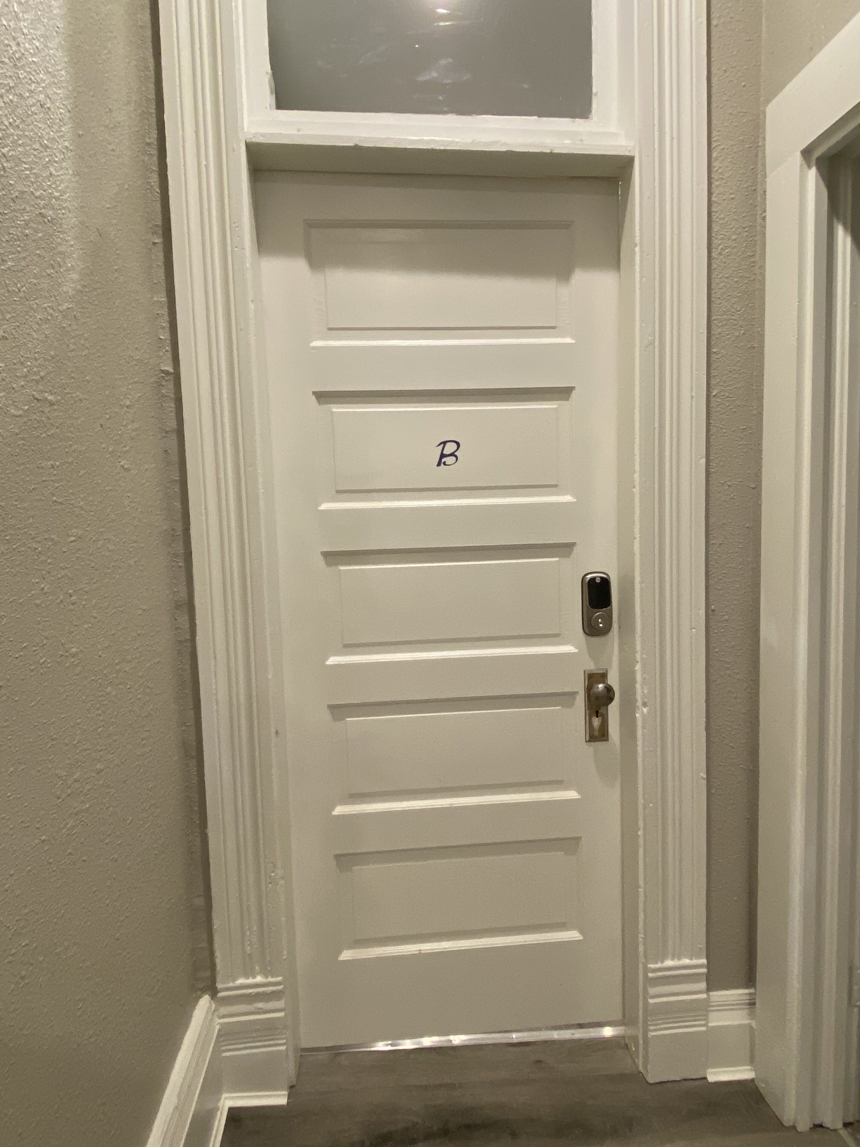 Une porte blanche avec la lettre « B » et un clavier à code.