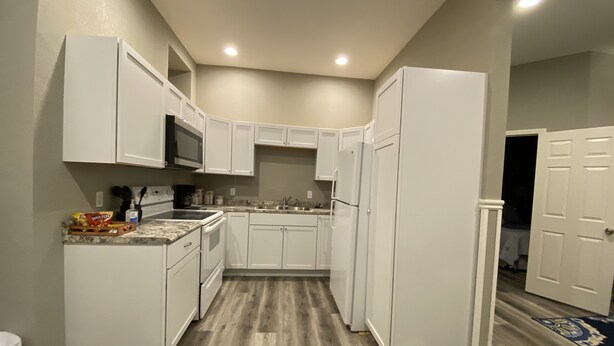 Una cocina compacta con armarios blancos, un microondas y un refrigerador.