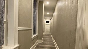 Un pasillo con piso alfombrado, molduras blancas y una puerta al final.
