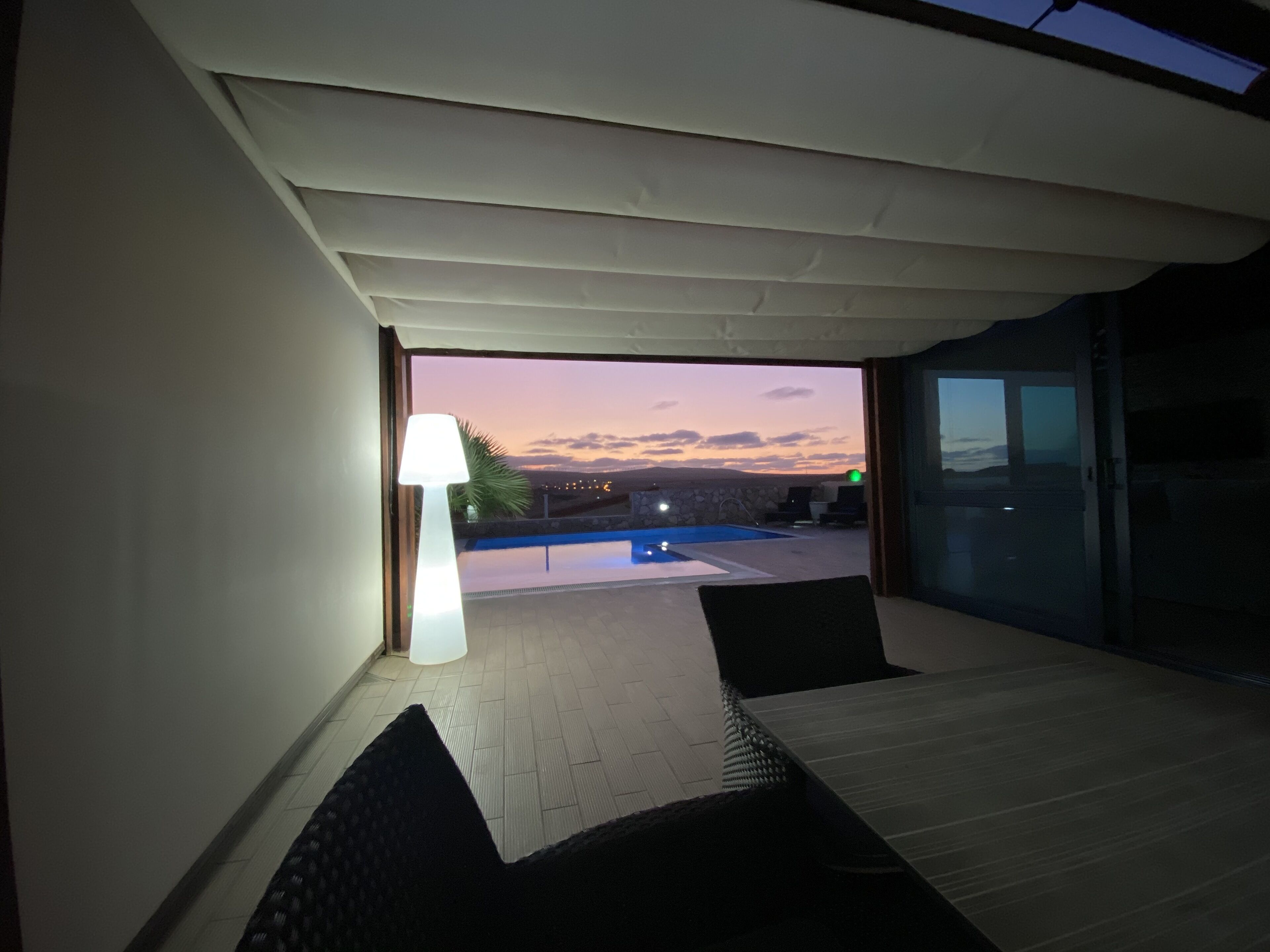 A room with a view of a swimming pool and sunset.