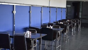 A row of tables and chairs in a room with blue partitions. - Hotel Pondichery (Puducherry)