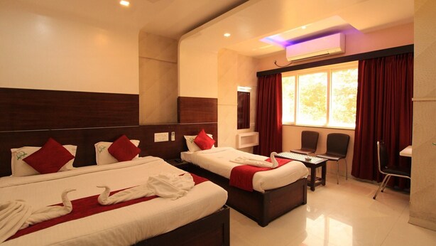 A hotel room with two beds, a desk, chairs, and a large window with curtains. - Hotel Pondichery (Puducherry)
