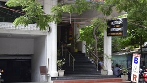 A building entrance with a staircase leading to a bar and restaurant named "Resto Bar A.C. Family Restaurant" with A.C. rooms available. - Hotel Pondichery (Puducherry)