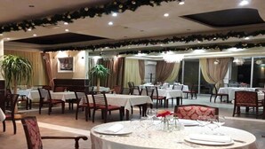 Un restaurante con mesas y sillas redondas, decorado con plantas y flores.