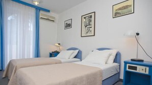 Habitación de hotel con dos camas, un escritorio con lámpara y cuadros en la pared.