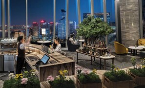 A rooftop bar with a city view, a bar counter, seating areas, and a coffee machine. - Conrad Hangzhou (Hangzhou)