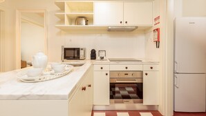A compact kitchen with white cabinets, a microwave, an oven, and a refrigerator. - Deluxe Apart with Balcony view to Flores Street (Oporto)