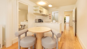 A modern kitchen with a round wooden table and grey upholstered chairs, a microwave, and a sink. - Deluxe Apart with Balcony view to Flores Street (Oporto)