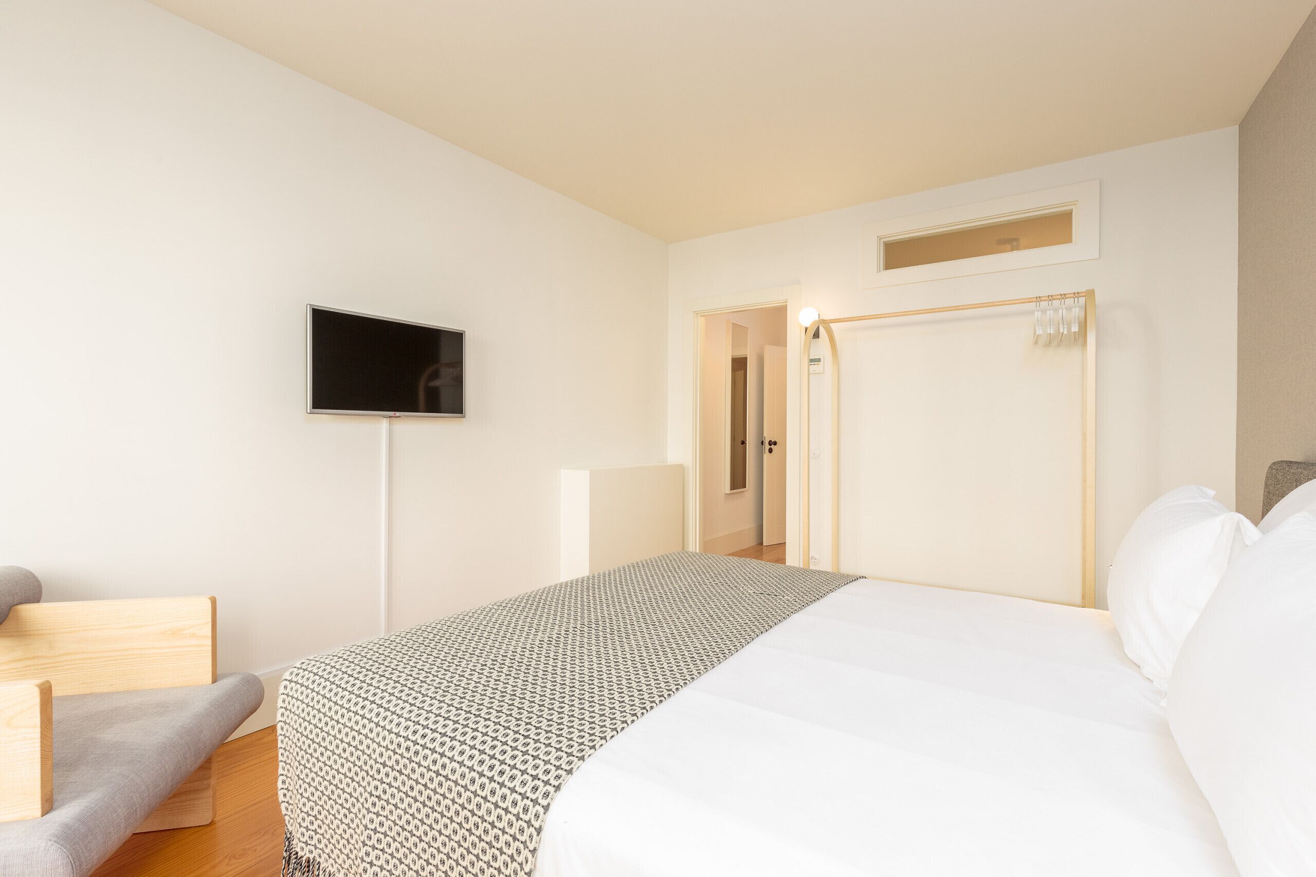 A bedroom with a bed, a TV, a bedside table, and a wardrobe.