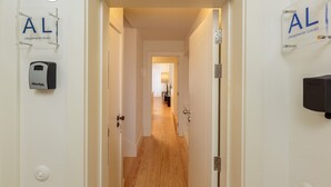 Un pasillo con suelo de madera y paredes blancas, con un letrero visible que indica 'AL' y 'Alojamento Local', mostrando una opción de alojamiento local.