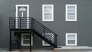 A building with a gray exterior, a black metal staircase, and white-framed windows.