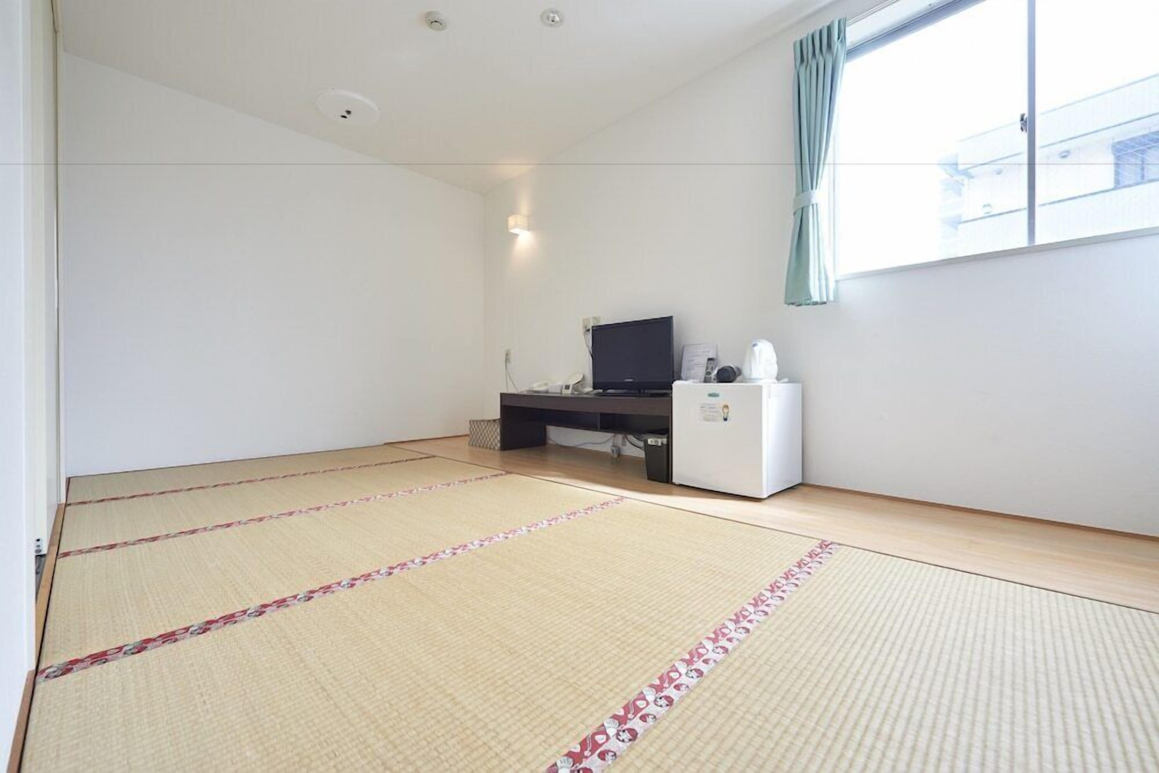 A room with tatami mats, a desk with a computer, a television, and a refrigerator.