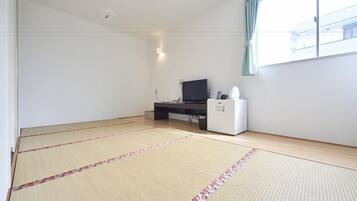 A room with tatami mats, a desk with a computer, a television, and a refrigerator.
