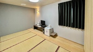 A room with tatami mats, a desk with a computer, a small table with a kettle, and a black curtain. - Hotel Select Inn Saitama Moroyama (Moroyama)