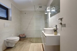 A modern bathroom with a toilet, sink, and shower.