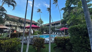 Un hotel con piscina rodeada de palmeras y sillas de descanso.