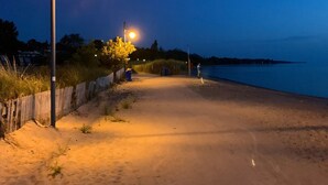 Ein Strandweg bei Nacht mit Straßenlaternen und einer Person, die spazieren geht.