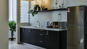 Een moderne keuken met zwarte kastjes, een roestvrijstalen koelkast, een inbouwoven en hanglampen.