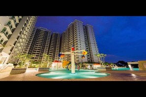 A residential building with a rooftop pool area featuring a water play structure.