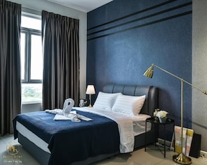 A hotel room with a large bed, a nightstand, a lamp, and a view of the outdoors through a window.