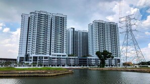 Een hoog appartementencomplex met verschillende balkons, een centrale binnentuin en een groot waterlichaam op de voorgrond.