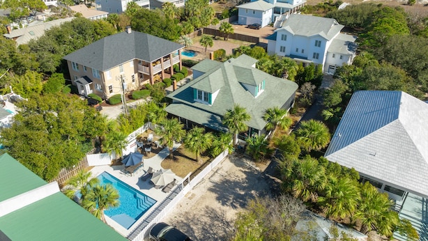 A residential area with houses, a swimming pool, and a beach in the background.
