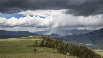 A mountainous landscape with a person walking on a grassy hill.