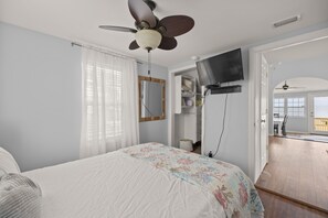 A bedroom with a bed, a ceiling fan, a TV, and a view of the outside. - Bayfront Vacation Home! (Gulf Shores)