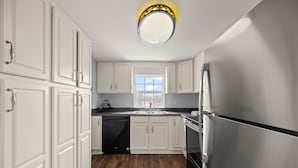 A kitchen with white cabinets, a stainless steel refrigerator, and a dishwasher.