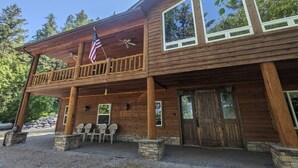 A wooden lodge with a balcony, a flag, and stone pillars. - Hanging Rock Get Away (Bigfork)