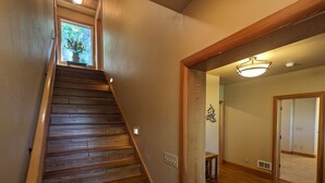 A wooden staircase leading to a room with a wooden floor and a ceiling light fixture. - Hanging Rock Get Away (Bigfork)