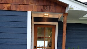 A wooden door with a glass panel, a number '131' above it, and a small porch with a light fixture. - Modern Lakefront Cottage on Open Water with Stunning Sunsets on Cedar Creek Lake (Trinidad)