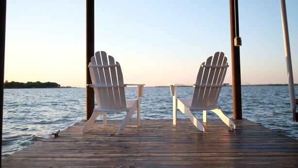Two Adirondack chairs on a wooden dock with a view of the water and a distant shoreline. - Modern Lakefront Cottage on Open Water with Stunning Sunsets on Cedar Creek Lake (Trinidad)