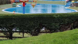Ein Schwimmbecken mit Rutschen und einem kleinen Gebäude mit der Aufschrift 'CHILDREN'S'.