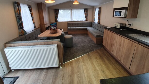 Ein kompaktes Wohnmobil-Interieur mit Küchenzeile, Sitzgelegenheiten und Esstisch.