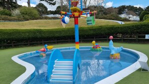 Ein Kinderspielbereich mit Pool, Rutschen und aufblasbaren Spielzeugen.